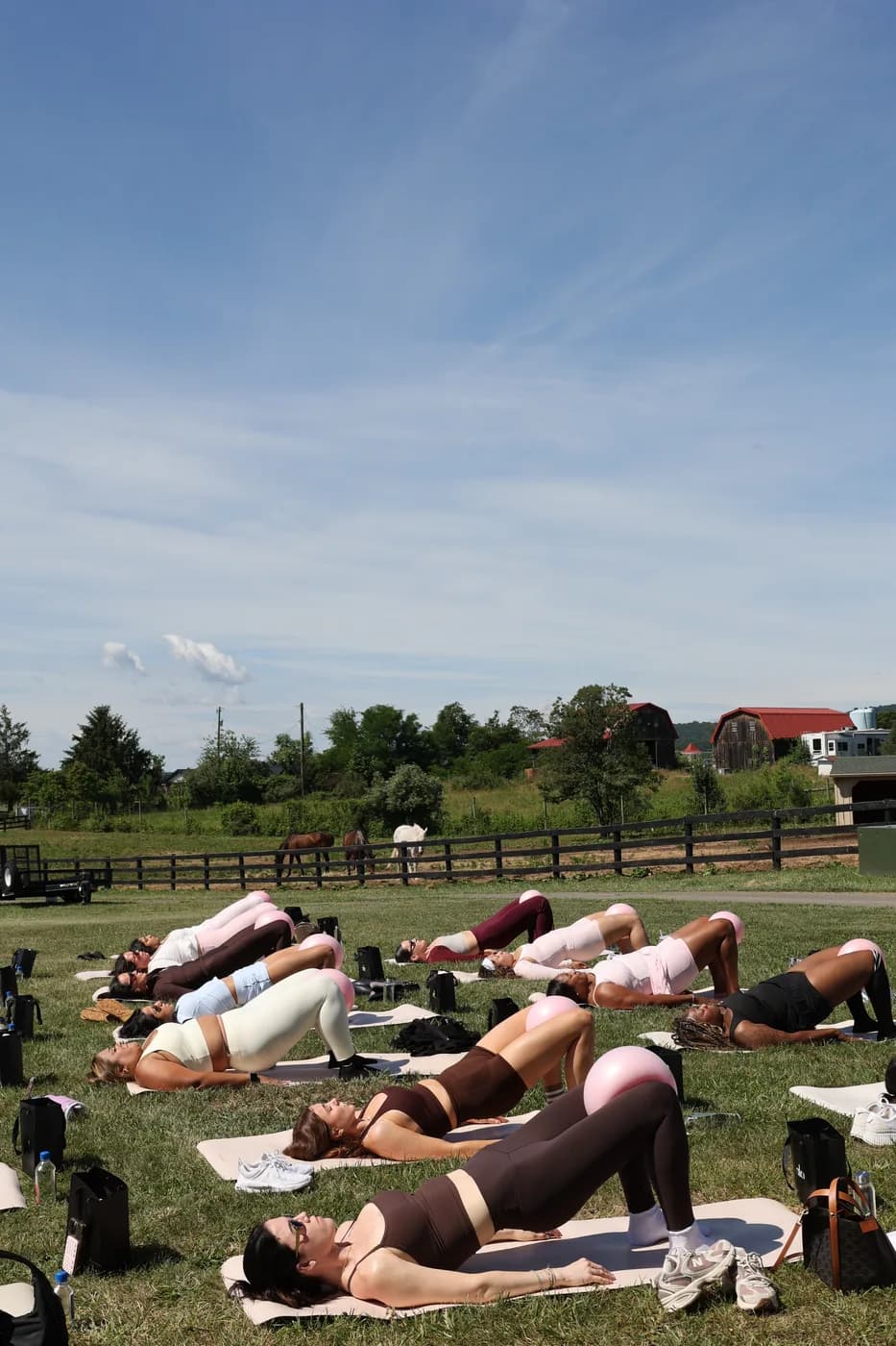 Sold-out outdoor mat Pilates class on a private Leesburg farm under a blue sky at a Mind & Body Retreats Horses & Pilates event